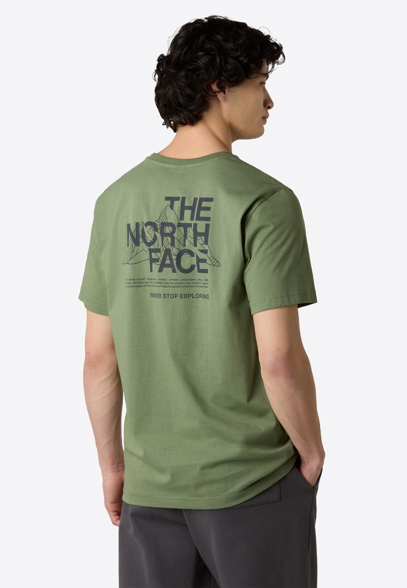 Mintgrön t-shirt med kort ärm och svart grafiktryck på baksidan, som visar bergsilhuetter samt texten "THE NORTH FACE" och "NEVER STOP EXPLORING."