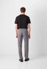 Grå elastisk livbåndbukser med to baklommer, kombinert med en svart t-skjorte. Buksene har en jevn tekstur og en tapered form.