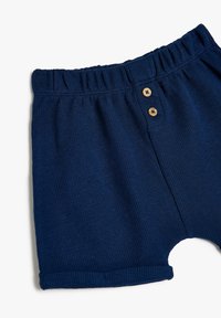 Mørkeblå strikkede shorts med elastisk talje, to træknapper foran og opsmøgedeærmer. Tekstureret stoffinish.