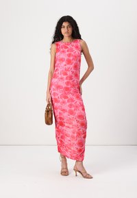 Garšs, bez piedurknēm, rozā kleita ar ziedu rakstu, gluda auduma un pieguļoša silueta. Valkāta ar strāpju papēžiem un turot brūnu rokassomu.