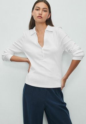 Witte polo met lange mouwen en V-hals, drie knopen en ribgebreide manchetten, gecombineerd met marineblauwe broek. Gladde textuur, slim fit ontwerp.