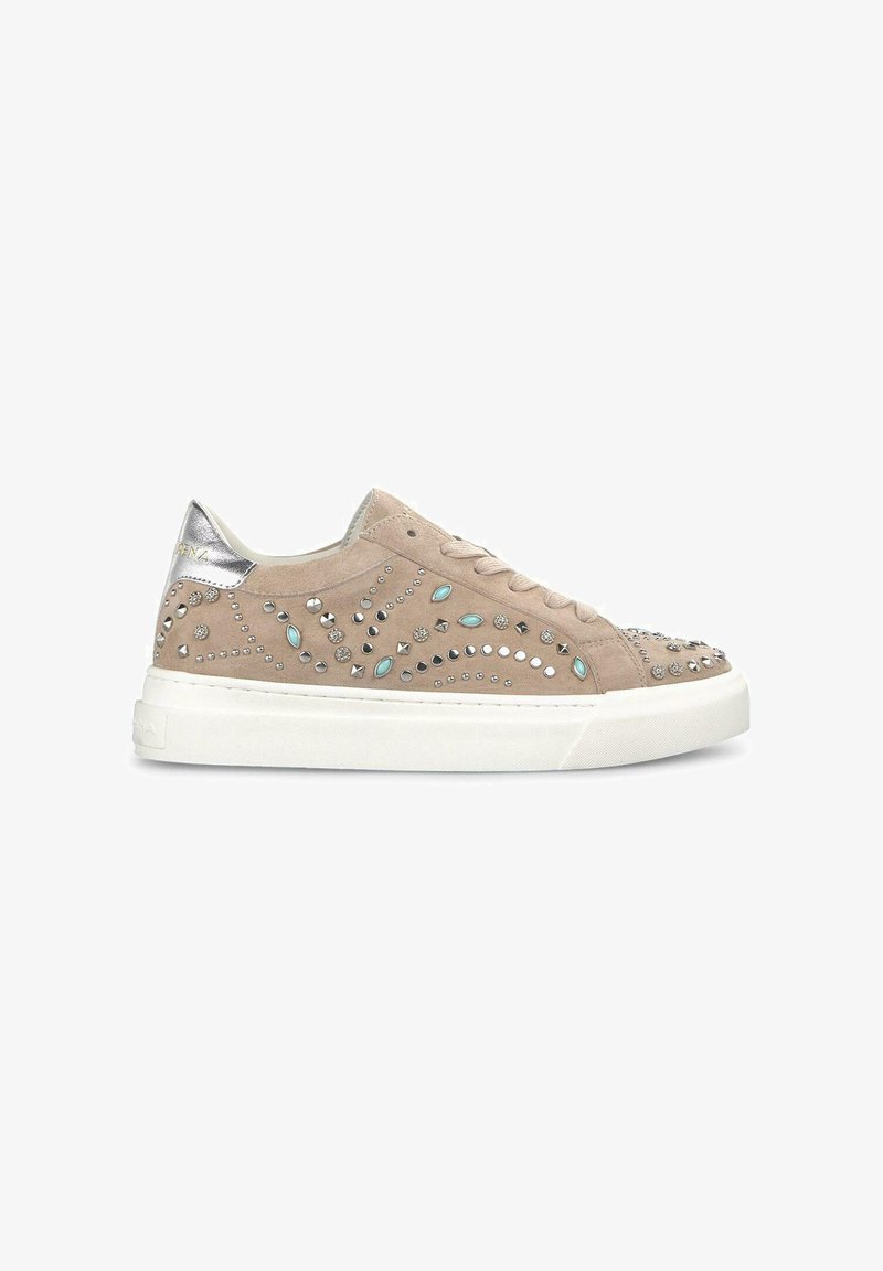 Zapatillas de ante beige con adornos de tachuelas, presentando un tirador de talón plateado y suela de goma blanca. Cordones y detalles texturizados presentes.