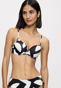 Set di bikini bianco e nero con un audace motivo astratto, caratterizzato da spalline regolabili e una texture liscia. Progettato per una silhouette aderente.