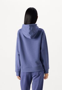 Felpa con cappuccio in morbido tessuto blu profondo. Presenta polsini e orlo a coste, con una vestibilità comoda e senza grafiche o motivi visibili.