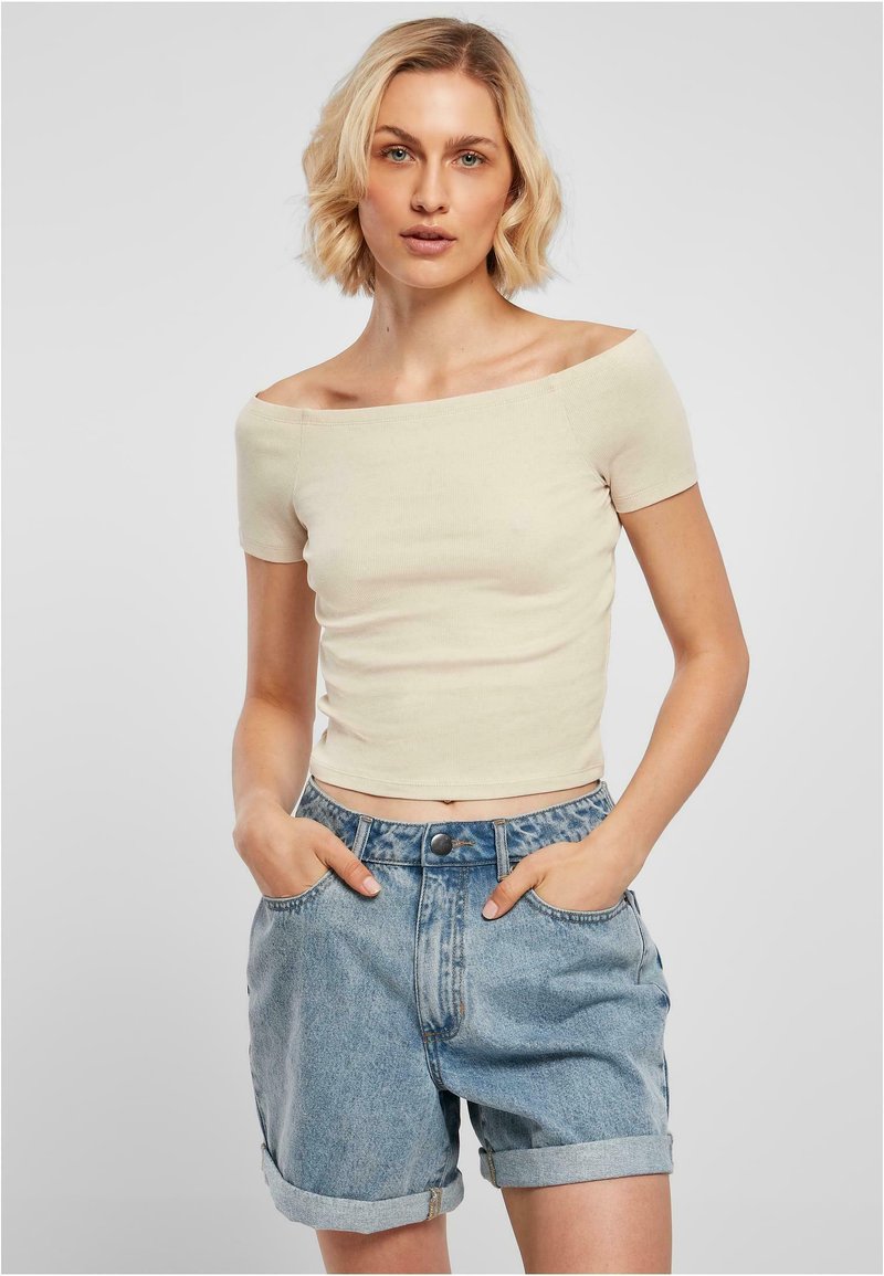 Krämfärgad av-axeln ribbad topp som kombineras med ljusblå denimshorts. Shortsen har upprullade fållar och framfickor.