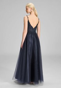 Suknia wieczorowa w kolorze granatowym o głębokim dekolcie z tyłu, złożona z misternych haftów koralikowych na korpusie oraz zwiewnej spódnicy z tiulu. Regulowane ramiączka.