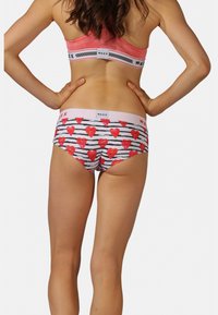 Ensemble de sous-vêtements multicolores comprenant une bande rose et un slip à motifs avec des cœurs rouges sur des rayures noires et blanches. Tissu doux, design décontracté.