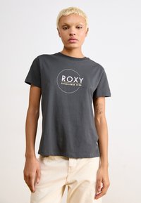 Pilkas prigludęs trumpomis rankovėmis marškinėliai, su apvaliu baltu ir rožiniu ROXY logotipu priekyje. Minkšta medvilnės audinio tekstūra.