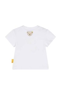 Camisa de algodón blanca con mangas cortas, con un parche de oso cosido en la parte de atrás y una pequeña etiqueta amarilla en el costado.