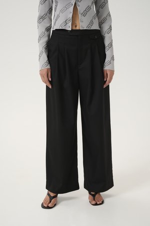 Black wide-leg trousers with pleats, featuring a smooth texture and a high waist. Paired with a grey patterned cropped top and black sandals.