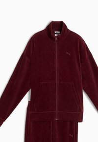 Burgundy corduroy zip-up jacket with a high collar, two front pockets, and subtle logo detail. Features vertical ribbed texture.