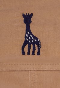Design di giraffa ricamata in blu navy su tessuto beige, con macchie di colore chiaro e contorni distintivi; texture morbida con una finitura liscia.