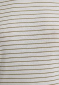 Gestreifter Oberteil aus leichtem Stoff, der abwechselnd dünne weiße und beige Streifen aufweist. Glatte Textur mit passender Form.