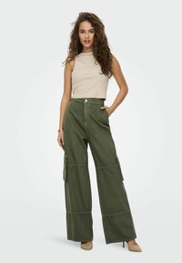 Olijfgroene cargobroek met brede pijpen, twee zijzakken en een hoge taille, gecombineerd met een aansluitend beige mouwloos topje. Glad textuur.