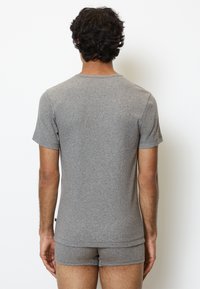 T-shirt grigio a maniche corte realizzato in tessuto misto cotone, con collo rotondo e una superficie liscia, abbinato a pantaloni corti grigi coordinati.
