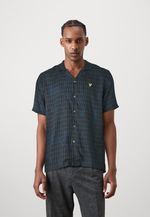 Camisa de manga corta abotonada en tela negra con un patrón de cuadros azules y un logo amarillo. Presenta un cuello y un corte relajado.
