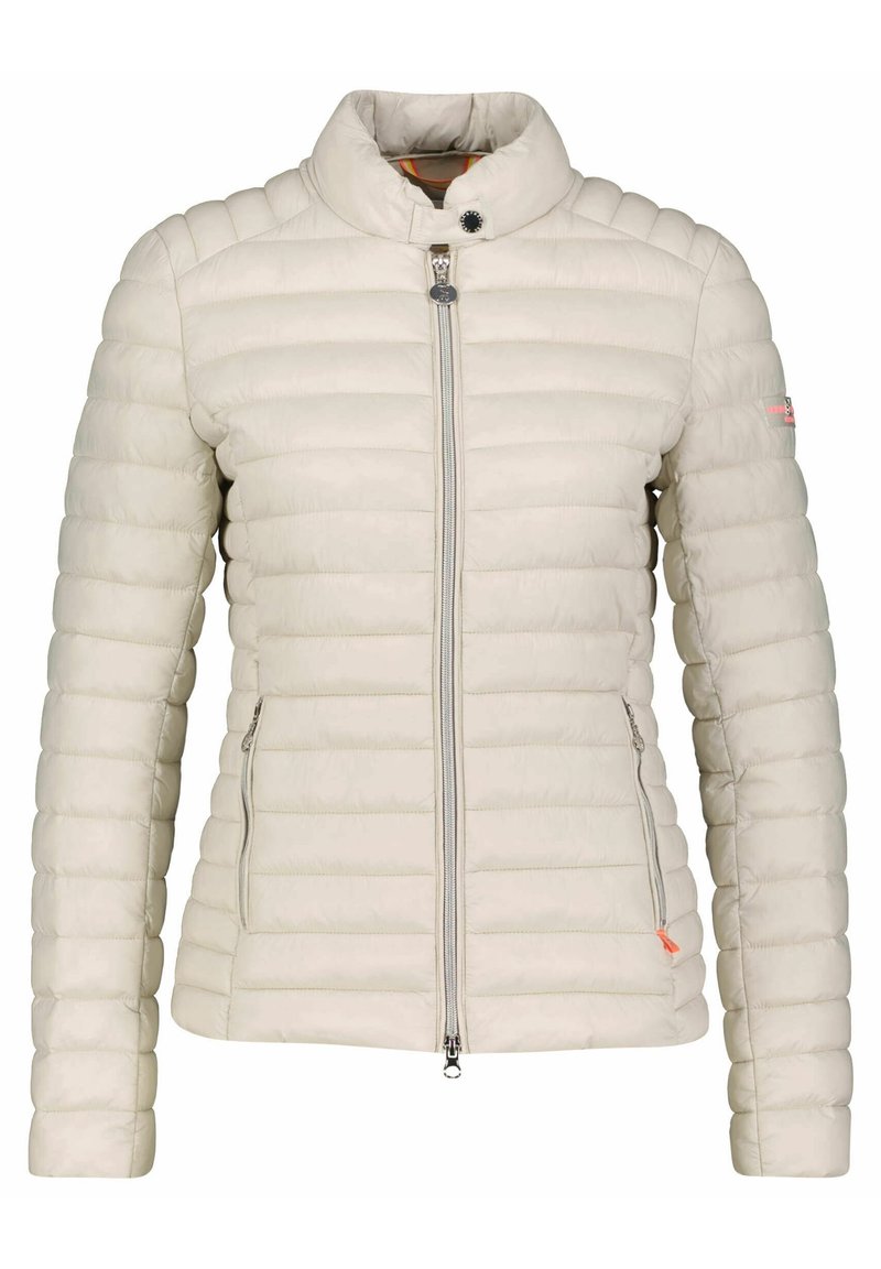 Chaqueta acolchada beige claro con diseño acolchado vertical, cuello alto, cremallera frontal y bolsillos laterales. Presenta un logo sutil en la manga.