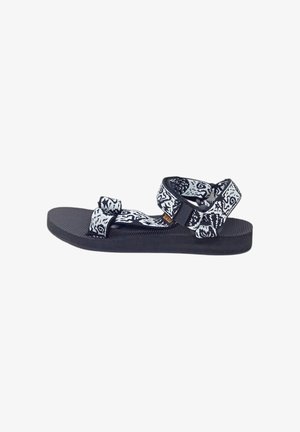 Schwarz-weiße Sandalen mit Muster, verstellbaren Riemen, einer strukturierten schwarzen Sohle und einem flachen Design, das sich gut für legere Kleidung eignet.