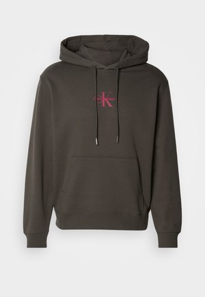 Sudadera con capucha de color gris oscuro, con un bolsillo frontal, capucha con cordón y logo de Calvin Klein en color rosa en el pecho. Material de algodón suave.