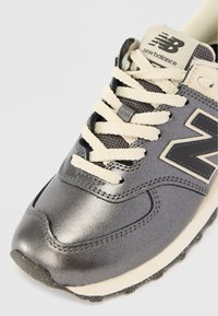 Hallide hallide New Balance'i sneaker, kreemjate paeltega, õmblustehnikaga, võrksuuga ja musta "N" logoga küljel.