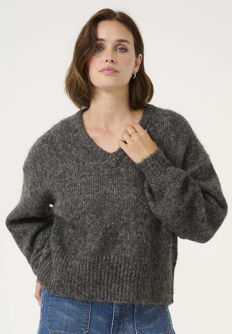 Pulover gri din tricot, texturat, cu decolteu în V și mâneci supradimensionate. Cuffuri și tiv ribbate, realizat dintr-un material moale și pufoasă.