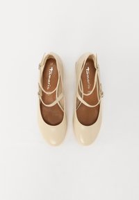 Beiga lackskinnsballetskor med tunna korslagda remmar, rund tå och brun inredning. Storlek märkts som 37. Slät textur.