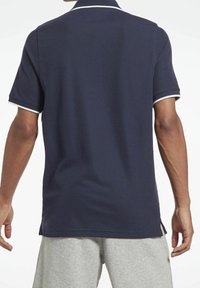 Námořnická polo tričko s klasickým límečkem, bílými lemy na rukávech a bočními rozparky na spodním lemu. Vyrobeno z texturované, prodyšné tkaniny.
