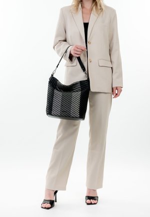 Sac hobo tissé noir avec une surface texturée, un sommet incurvé et une bandoulière réglable, présenté sur un fond blanc uni.