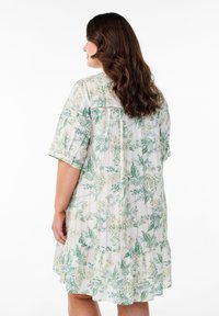 Robe florale en tissu léger avec des motifs botaniques verts et jaunes, manches courtes et ourlet à volants, avec des détails en dentelle au dos.