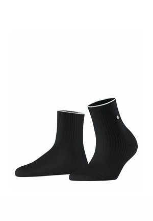 Paire de chaussettes courtes noires côtelées avec un petit logo rond argenté sur le côté extérieur, présentées sur un fond blanc.