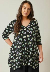 Schwarzes Oberteil mit V-Ausschnitt und Dreiviertelärmeln. Hat ein florales Muster in Weiß, Grün und Lila. Ausgestellter Schnitt mit asymmetrischem Saum.