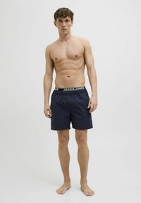 Tengerészkék úszósort, elasztikus derékpánttal, "JACK & JONES" logóval, könnyű anyagból és oldalsó zsebbeli részlettel.