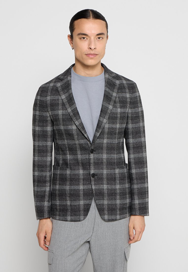 Grau kariertes Sakko mit taillierter Passform, ausgestattet mit einem Reverskragen, zwei Knöpfen und zwei Fronttaschen; getragen über einem hellgrauen Hemd.