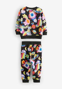 Fleece-Pyjama-Set mit schwarzem Hintergrund und lebhaften, mehrfarbigen Weltraummotiven, darunter Raketen, Planeten und Sterne.
