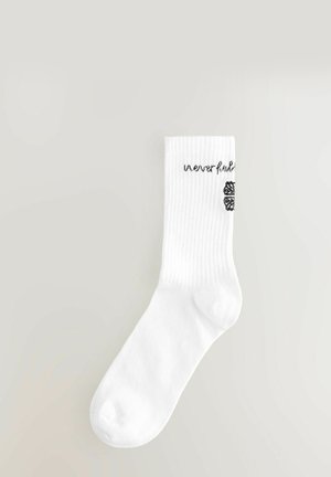Witte katoenen sok met ribbelstructuur, voorzien van de bedrukte zwarte tekst "neverfull" en een decoratief zwart ontwerp aan de zijkant.