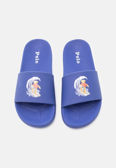 Μπλε σανδάλια με λουράκια που έχουν γραφικό από αρκούδα σέρφερ και την επιγραφή "Polo" στη σόλα.