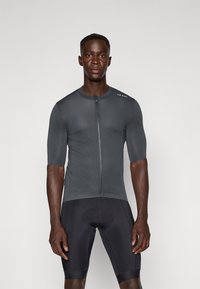 Maillot de cyclisme pour hommes, à manches courtes, design ajusté, tissu texturé gris foncé, fermeture éclair mi-longue, associé à un cuissard de cyclisme noir.