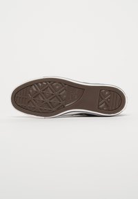 Bruine rubberen zool van een sneaker met een textuurpatroon, witte zijaccenten en een platte vorm met afgeronde hoeken.