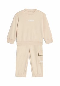 Beżowy zestaw składający się z bawełnianej bluzy i spodni. Bluza ma okrągły dekolt i ściągacze na rękawach; spodnie mają kieszeń typu cargo i elastyczne mankiety.