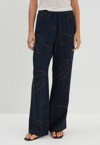Pantalon marine avec une finition texturée, caractérisé par un motif abstrait marron, une coupe large et une taille élastique pour le confort.