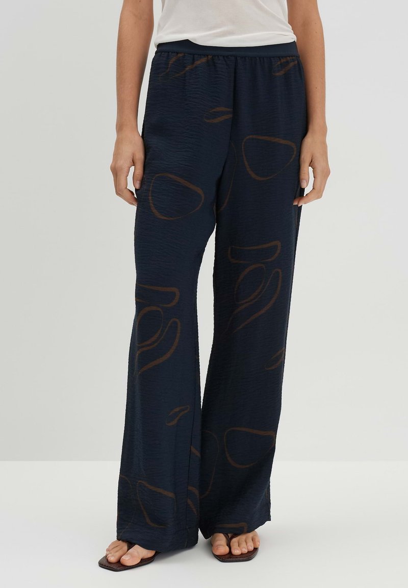 Pantalon marine avec une finition texturée, caractérisé par un motif abstrait marron, une coupe large et une taille élastique pour le confort.
