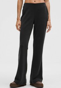 Čierne rozšírené nohavice z mäkkého, pružného materiálu so stranovými vreckami a vysokým pásom, s precíznym šitím pozdĺž švov.