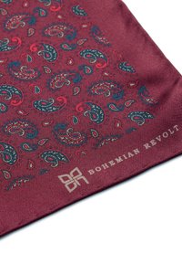 Burgundy paisley silk pocket square yang menampilkan pola biru, hijau, dan merah. "Bohemian Revolt" dicetak dalam warna putih di sudut.