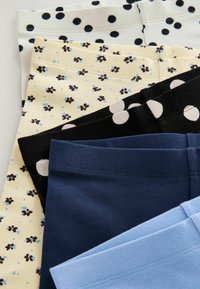 Fünf gefaltete Leggings in Weiß mit schwarzen Punkten, Creme mit kleinem Blumenmuster, Schwarz mit großen weißen Punkten, Marineblau und Hellblau.