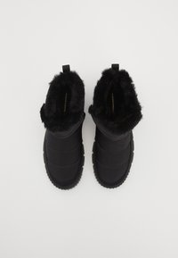 Schwarze isolierte Stiefel mit Kunstfellfutter, gestepptem Design, runder Zehenpartie und Zuglasche. Strukturiertes Gummiband für Halt und Langlebigkeit.