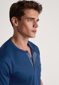 Marineblauwe t-shirt met een knoopsluiting aan de Henley-hals, voorzien van een inzet met geometrisch patroon, korte mouwen en een borstzak. Glad van textuur.