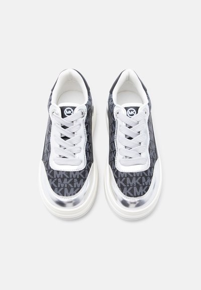 Ζευγάρι μαύρα και ασημί αθλητικά παπούτσια με άσπρα κορδόνια, με επαναλαμβανόμενο μοτίβο "MK" και λογότυπο "MK" στη γλώσσα, απόψη.