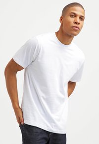 Hvid bomulds t-shirt med korte ærmer, normal pasform, rund hals design, glat tekstur og minimalistisk stil. Bæres med mørke jeans.
