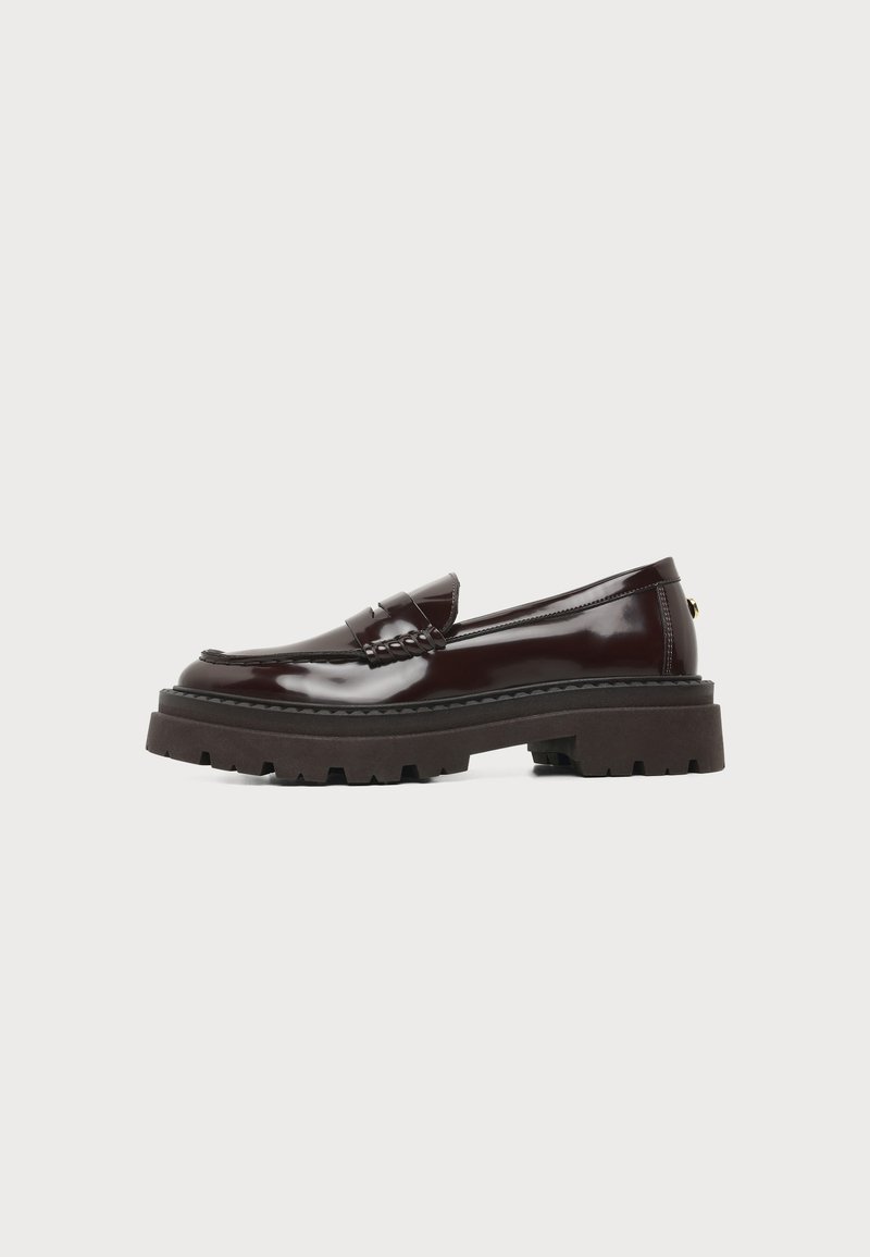 Mocassin en cuir brillant marron foncé avec semelle épaisse crantée et détail de bride penny, vu de côté sur un fond uni.