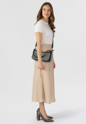 Sac à main croisé en cuir noir avec un motif géométrique gris texturé, présentant un rabat incurvé et une bandoulière ajustable.